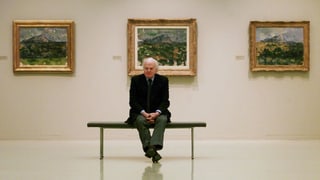 Eberhard Kornfeld sitzt in einem Museum vor drei Cezanne-Bildern.