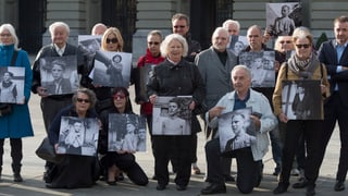 Ehemalige Verdingkinder und Opfer fürsorgerischer Massnahmen posieren mit Kinderfotos vor dem Bundeshaus.