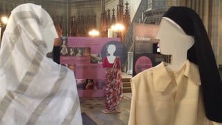 Zwei verschleierte Holzpuppen. Eingekleidet als Muslima und als Nonne.