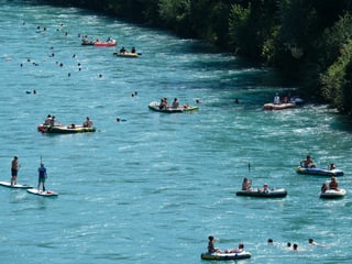 Viele Schwimmer und Boote auf einem Fluss bei heissem Wetter