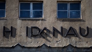 Die Fassade eines Gebäudes in Heidenau, die Aufschrift mit dem Ortsnamen fällt auseinander. 