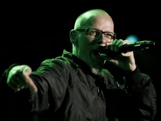 Mann Nahe mit Mikrophon am Singen, er trägt eine Sehbrille mit dunklem Rahmen