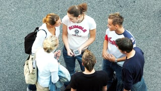 Eine Gruppe aus Mädchen und Jungs steht in einem Kreis und ist am Tratschen.
