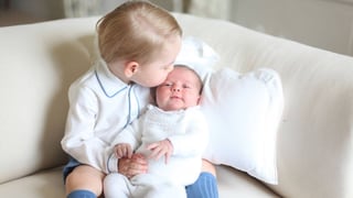 Baby Charlotte sitzt auf Georges Knien. Er küsst Charlotte auf den Kopf.