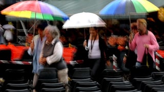 Menschen mit bunten Regenschirmen auf Tribüne.