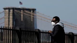 Mann mit Maske schaut zur Brooklyn Bridge.