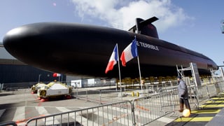 Ein schwarzes U-Boot mit dem Namenszug «Le Terrible» und zwei französischen Flaggen stehen hinter Abschrankungen.