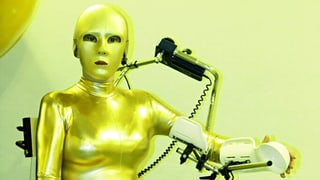 Eine Frau in roboterhaftem Goldkostüm. Eine Frau in roboterhaftem Goldkostüm.