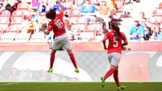 Die Schweizer Nati-Spielerin Fabienne Humm mit der Nummer 16 auf dem roten Trikot springt am FIFA World Cup 2015 vor der Zuschauertribüne in die Luft, rechts daneben Teamkollegin Noëlle Maritz mit der Nummer 5.
