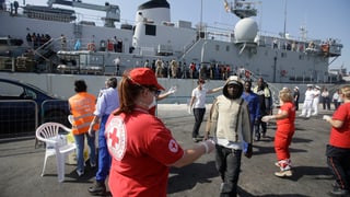 Angestellte vom roten Kreuz kümmern sich um Bootsflüchtlinge.