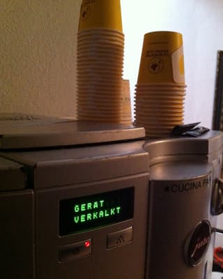 Eine Kaffeemaschine. Eine Anzeige lecuhtet mit der Schrift «Gerät verkalkt».