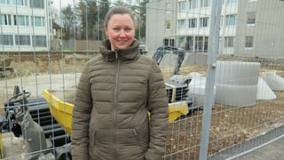 Frau in Mantel vor Baustelle Frau in Mantel vor Baustelle