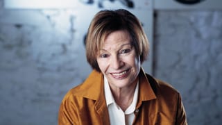 Frau mit ockerfarbenem Seidenhemd.