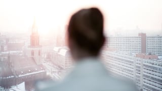 Silhouette einer Frau vor dem Panorama einer Grossstadt. 