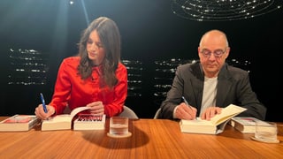 Eine Frau und ein Mann unterschreiben Bücher