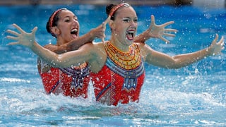 Synchronschwimmerinnen mit ausgestreckten Händen.