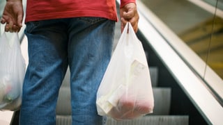 Mann auf Rolltreppe mit Plastiktüten