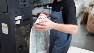 Ein Arbeiter hält einen Druck-Bogen.