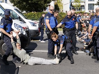 Polizei trägt Frau weg, die an Sitzstreik auf Strasse teilgenommen hatte.
