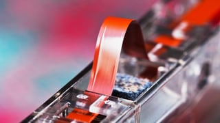 Ein Magnetstreifen, der leicht angehoben aus einer Audio-Kassette schaut.