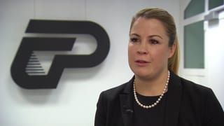 Frau mit schwarzem Jackett und Perlenkette im Interview. Frau mit schwarzem Jackett und Perlenkette im Interview.