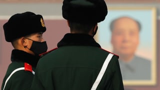 Polizisten mit Mundschutz vor einem Mao-Bild. 