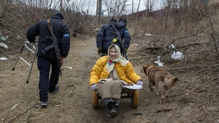 Ukrainische Soldaten evakuieren eine Frau aus der Stadt Irpin.