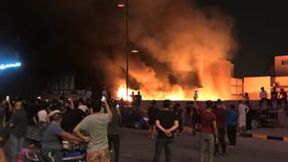 Protestierende stehen vor einem Brand in Bagdad. Protestierende stehen vor einem Brand in Bagdad.