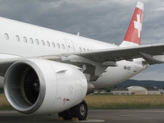 Heck und Triebwerk einer Swissmaschine, im Hintergrund der Hangar von Dübendorf