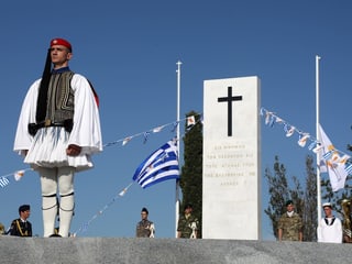 Ein Soldat in Tracht steht vor einem Denkmal.