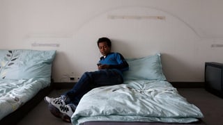 Ein Asylsuchender sitzt auf einem Bett