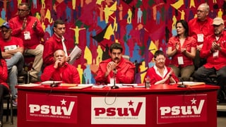 Präsident Maduro sitzt auf einem Podest umgeben von anderen Sozialisten.