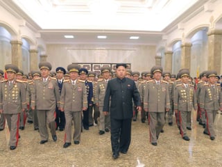 Kim Jong-un mit einer Gruppe von Menschen in Uniform in einem Palast.