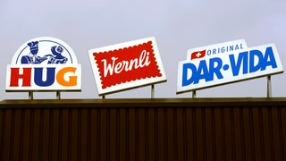 Die Werbeschilder von Hug, Wernli und Dar-Vida nebeneinander auf einem Dach.