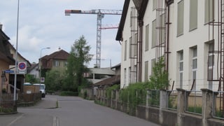 Strasse mit alten Häusern und Fabrik, im Hintergrund Baukran