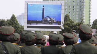 Uniformierte schauen auf einen grossen Bildschirm, der eine Rakete zeigt.