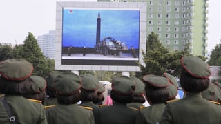 Uniformierte schauen auf einen grossen Bildschirm, der eine Rakete zeigt. Uniformierte schauen auf einen grossen Bildschirm, der eine Rakete zeigt.