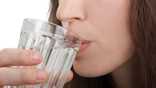 Eine Frau trinkt ein Glas Wasser