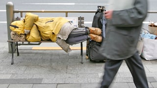 Ein Geschäftsmann geht an einem obdachlosen Mann vorbei, der auf einer Bank schläft. (reuters)