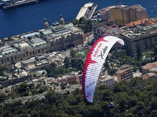 Ein Gleitschirmpilot der X-Alps noch weiter über der Stadt Monte Carlo in Monaco.