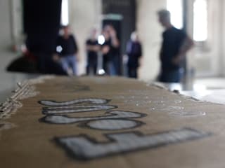 Schild mit Aufschrift "Focus" im Vordergrund, Menschen unscharf im Hintergrund.