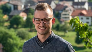 Ein junger Mann mit Brille, unscharf im Hintergrund ein Dorf. Ein junger Mann mit Brille, unscharf im Hintergrund ein Dorf.