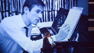 Udo Jürgens im Frack an Flügel sitzend. Im Hintergrund sieht man ihn auf einer Leinwand als junger Komponist, der ebenfalls am Flügel sitzt und Noten zu Papier bringt. 