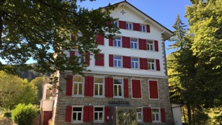 Kurhaus Balmberg: stattliches Haus, rote Fensterläden, blauer Himmel und Sonnenschein