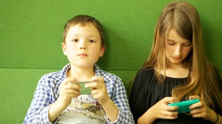 Zwei Kinder spielen mit Iphones.