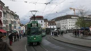 Barfüsserplatz mit wartenden Menschen und auf beiden Seiten der Tramstation ein Tram.