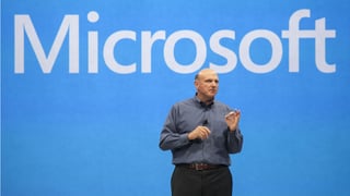Steve Ballmer steht vor einem blauen Hintergrund auf dem Microsoft steht.