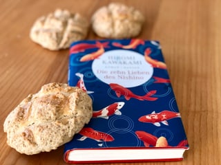 Der Roman «Die zehn Lieben von Nishino» von Hiromi Kawakami liegt auf einem Tisch, angelehnt am Buch ein japanisches Melonpan - ein weiche Biskquitkugel. Der Roman «Die zehn Lieben von Nishino» von Hiromi Kawakami liegt auf einem Tisch, angelehnt am Buch ein japanisches Melonpan - ein weiche Biskquitkugel.