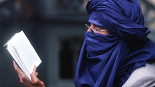 Ibrahim al-Konis Kopf ist in ein blaues Tuch gehüllt. Er liest. Man sieht ihn von der Seite.