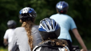 Drei Velofahrer mit Helm von hinten aufgenommen.